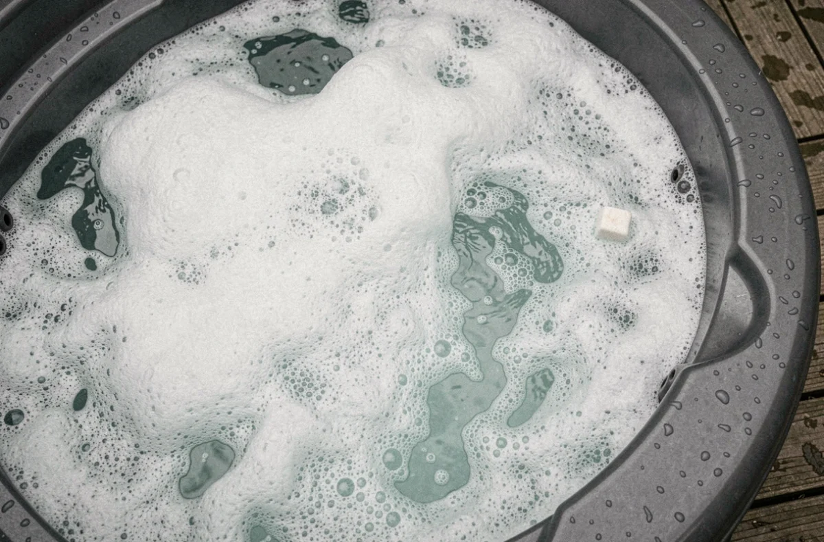 Vue aérienne rapprochée d'un spa avec mousse excessive et eau trouble causées par un surdosage de produit choc désinfectant