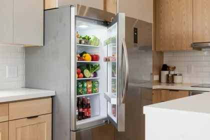Réfrigérateur américain en inox ouvert dans une cuisine contemporaine avec plan de travail en quartz blanc